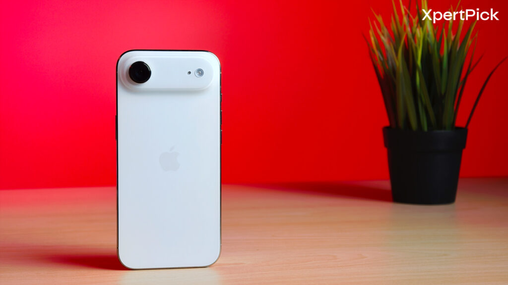 Apple iPhone Air in white standing on a tabletop, showcasing the rear design with the horizontal camera bar against a red background (Source: Yetnesh Dubey / XpertPick)